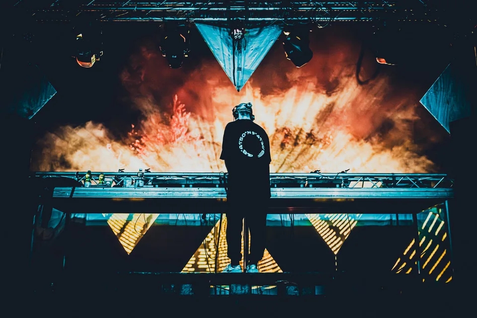 DJ als Silhouette vor Feuerwand