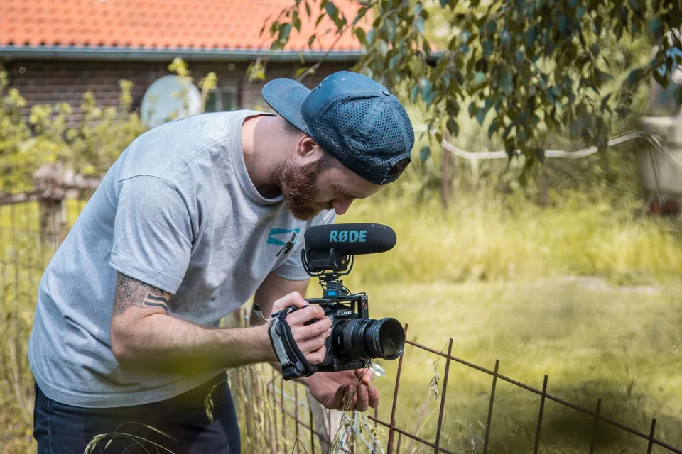 Videograf mit Kamera am Zaun